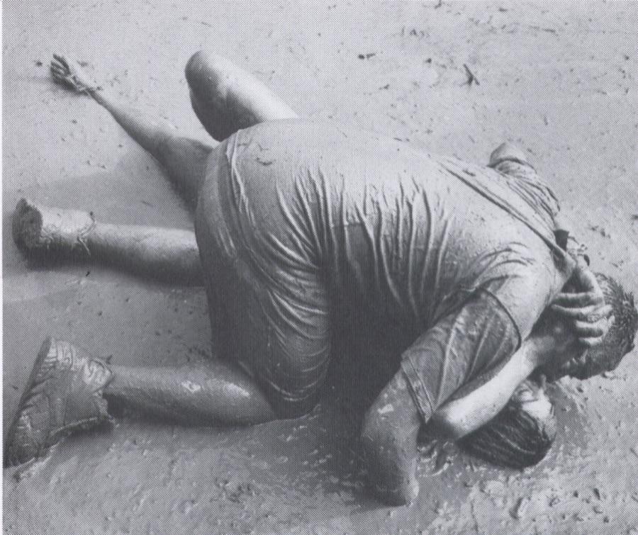 Two mud-covered festivalgoers embracing in the mud at Woodstock '94